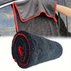 A rolled black microfiber car drying towel with red trim is shown next to a hand holding a car door.