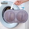 A gray mesh laundry bag is being placed inside a washing machine drum.