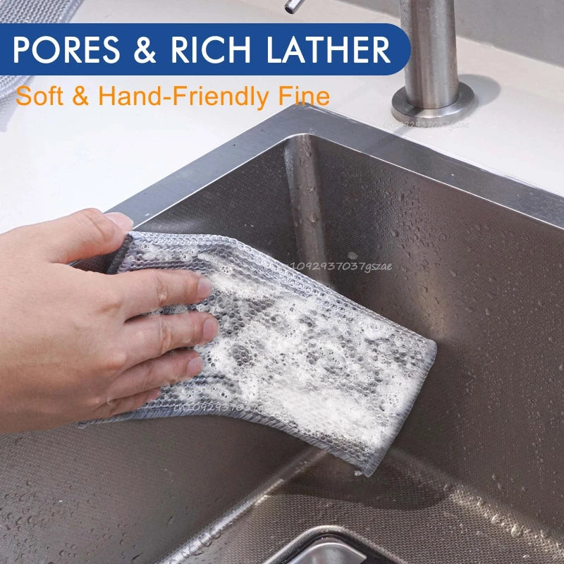 A hand is holding a white, porous cleaning pad in a stainless steel kitchen sink.