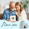 A smiling elderly man and a young woman embracing while holding a heart-shaped acrylic keepsake plaque.