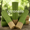 A stack of green citronella oil sticks, cylindrical in shape, are displayed on a wooden surface.