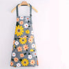 Gray apron with a floral print featuring yellow and white daisies, hanging on a wooden hanger.
