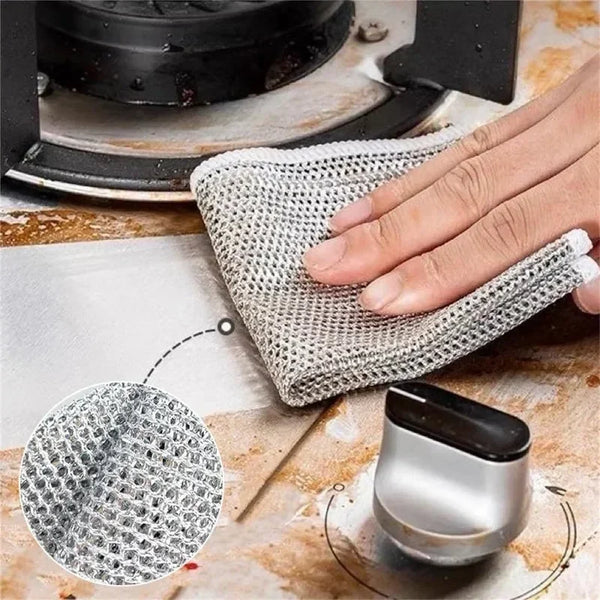 A hand is holding a mesh cleaning cloth used to clean a double-layer steel wire dish.