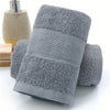 A stack of gray ultra-absorbent pure cotton bath towels with textured surfaces.