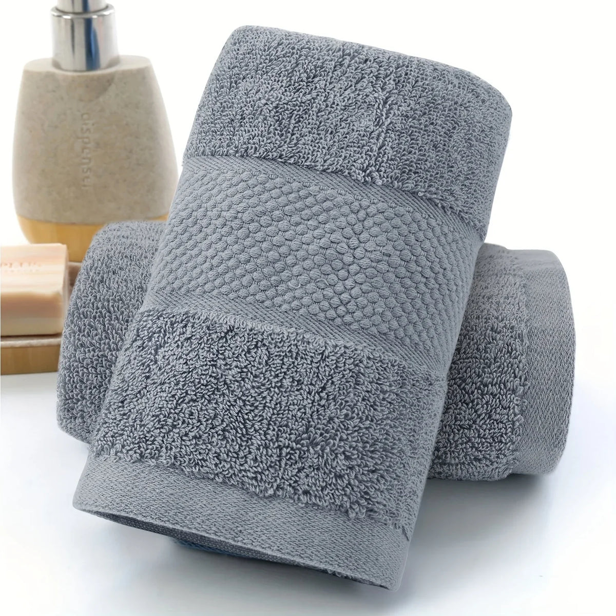 A stack of gray ultra-absorbent pure cotton bath towels with textured surfaces.