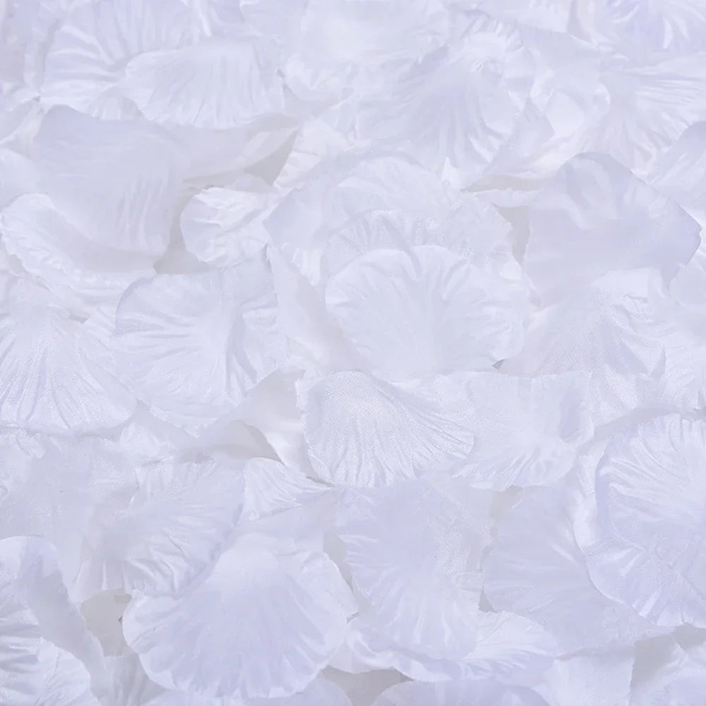 Pétalos de rosa de seda artificial blanca esparcidos sobre una superficie.