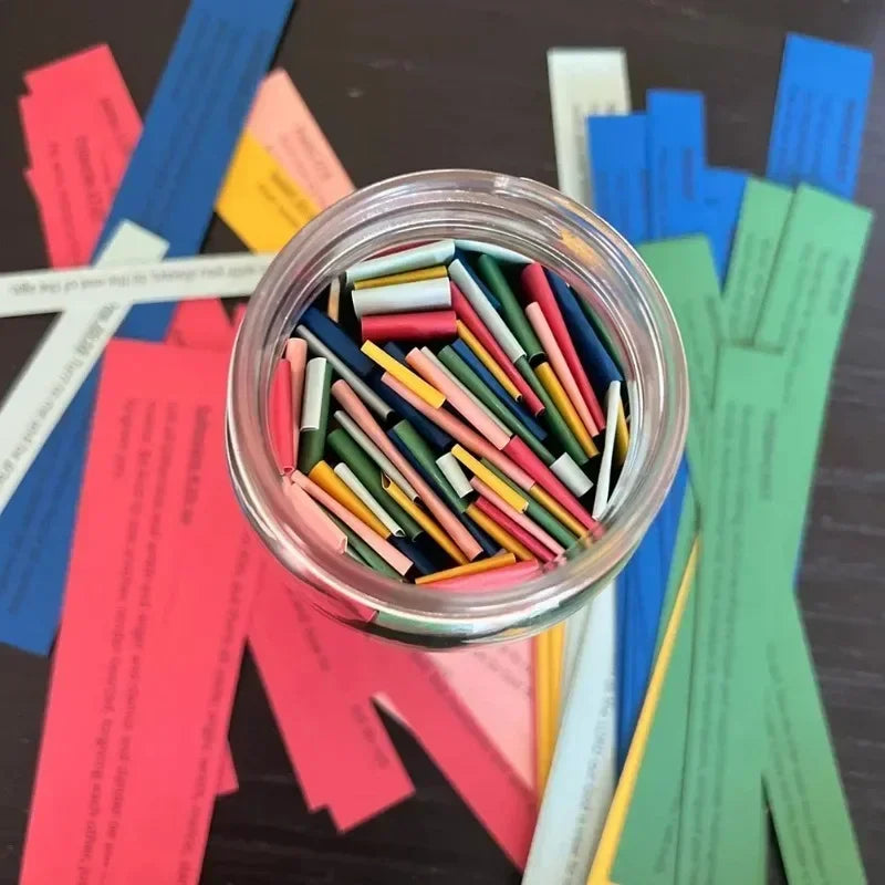 A clear jar filled with colorful scripture verses cards in various shades of red, blue, green, and yellow.