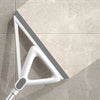 A silver silicone window and surface cleaner is shown angled against a light beige tiled surface.