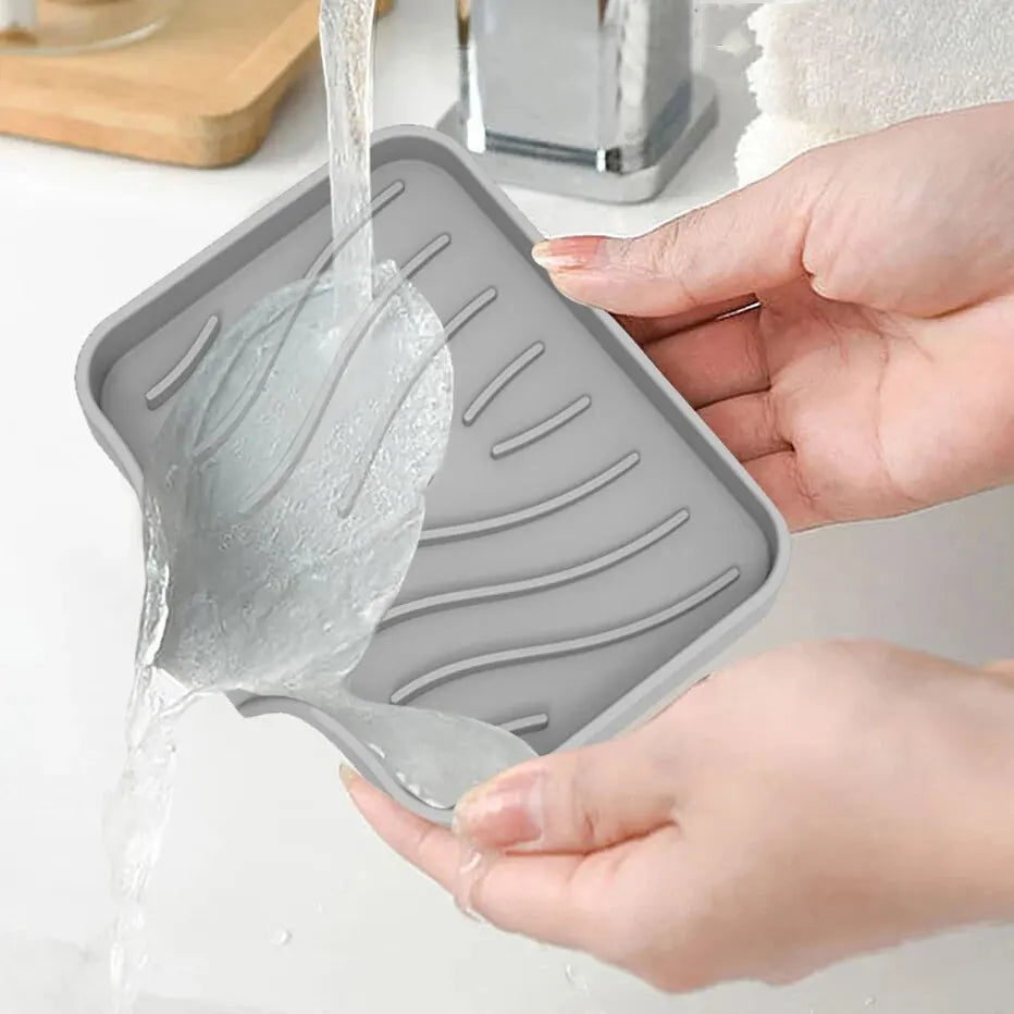 Hands are pouring water into a silicone draining soap tray organizer.