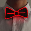 A close-up of a person wearing a white shirt with a glowing red bow tie accessory.
