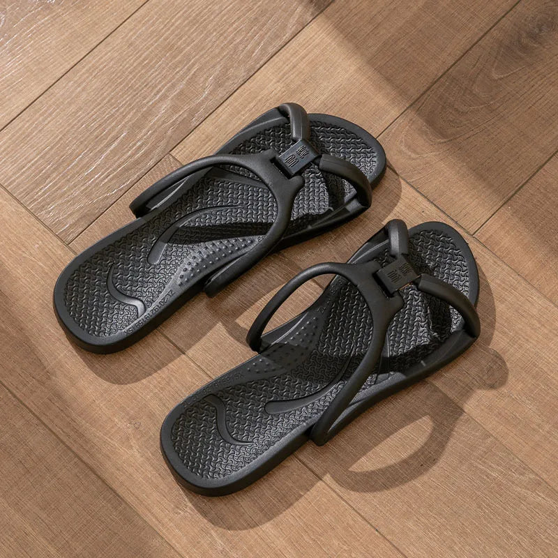 Une paire de tongs pliables en EVA noires posées sur une surface en bois.
