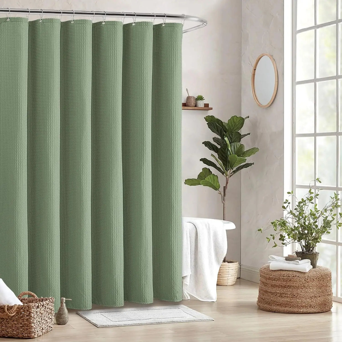 A set of light sage green waffle weave shower curtains hanging on a metal rod in a bathroom setting.