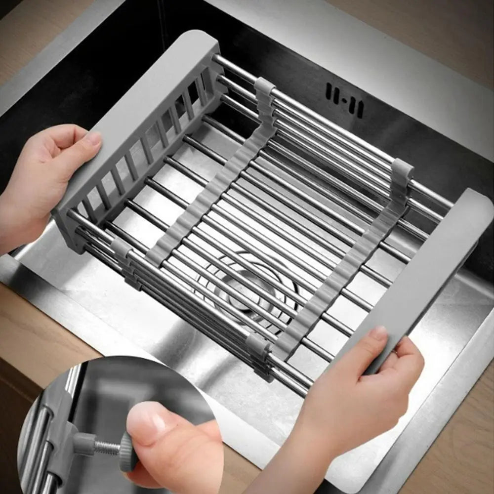 Hands are assembling an extendable stainless steel sink drain basket within a metal frame.