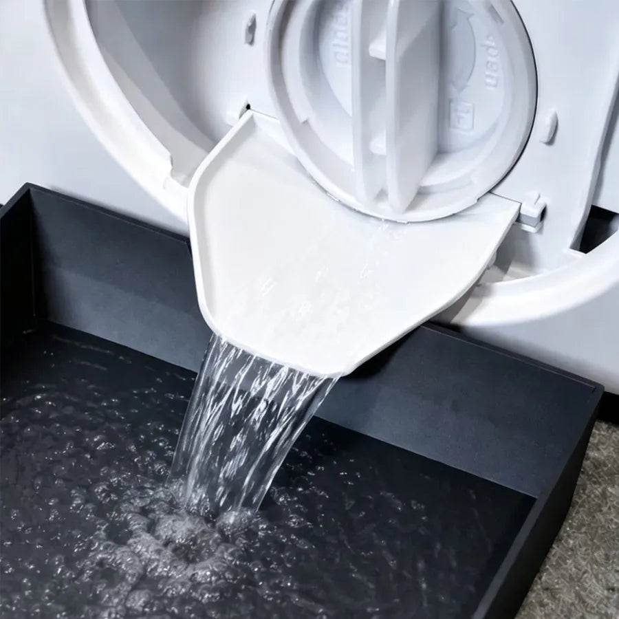 Un juego de bandeja y embudo blanco vertiendo agua en la bañera de una lavadora.