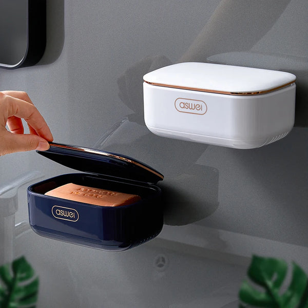 A hand is placing a dark blue double-layer drain soap holder rack onto a light gray wall surface.