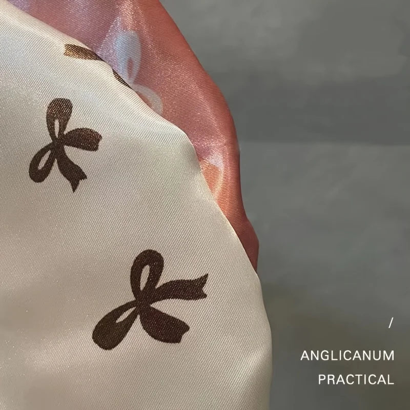 Close-up of a light beige fabric with dark brown ribbon embroidery, used as reusable double layer shower caps for hair.