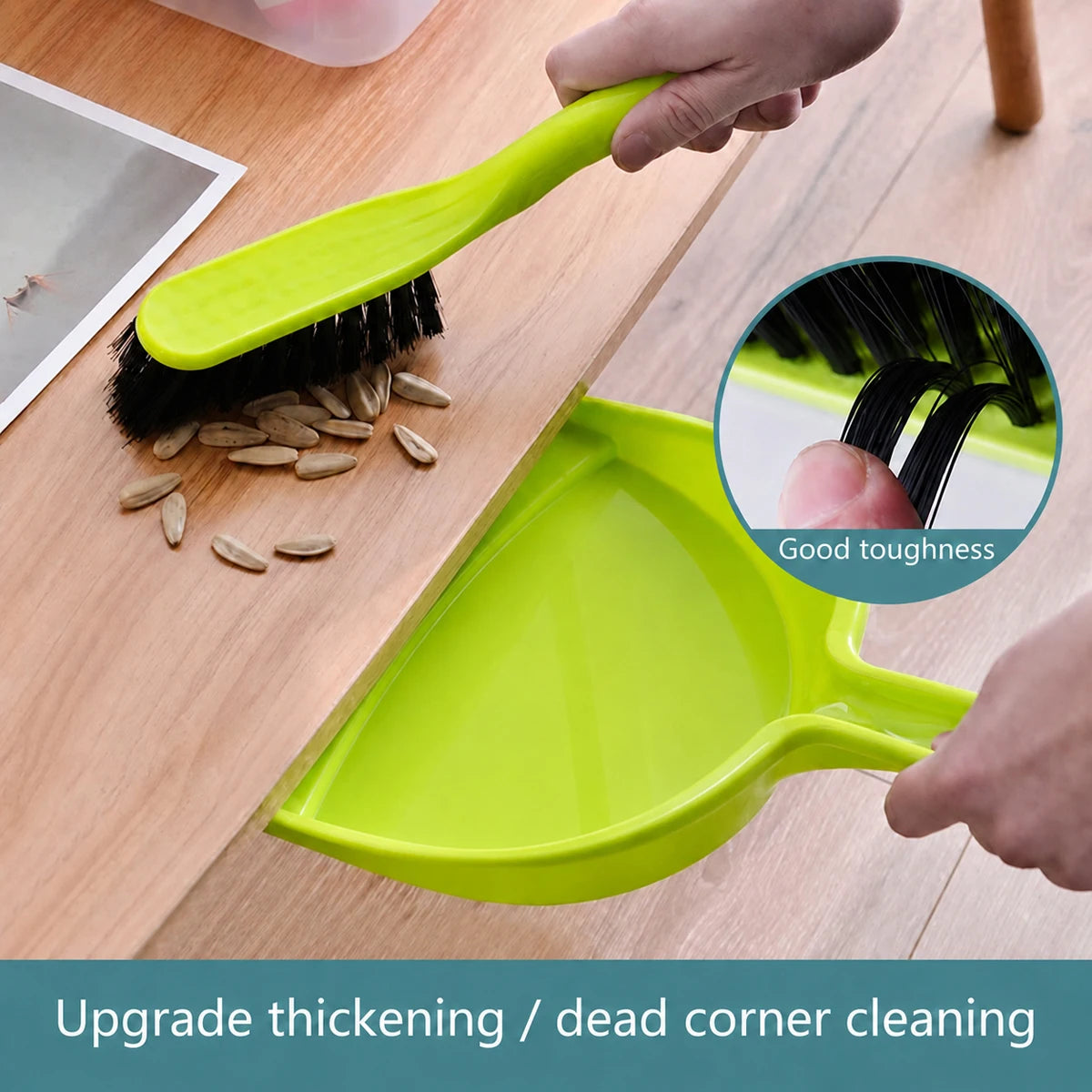 A hand is using a bright lime green mini handheld dustpan and brush set to clean a desk surface.