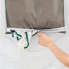 A hand is opening a gray fabric laundry organizer to hang white towels.