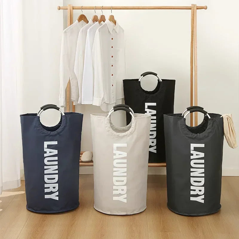 Three fabric laundry baskets in navy, beige, and black hanging on a wooden rack.