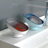 A set of suction cup soap dishes in light blue and gray colors sitting on a white countertop.