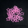 A pile of pink glow in the dark 3D star wall decals scattered on a black surface.