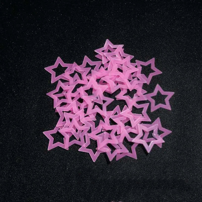 A pile of pink glow in the dark 3D star wall decals scattered on a black surface.