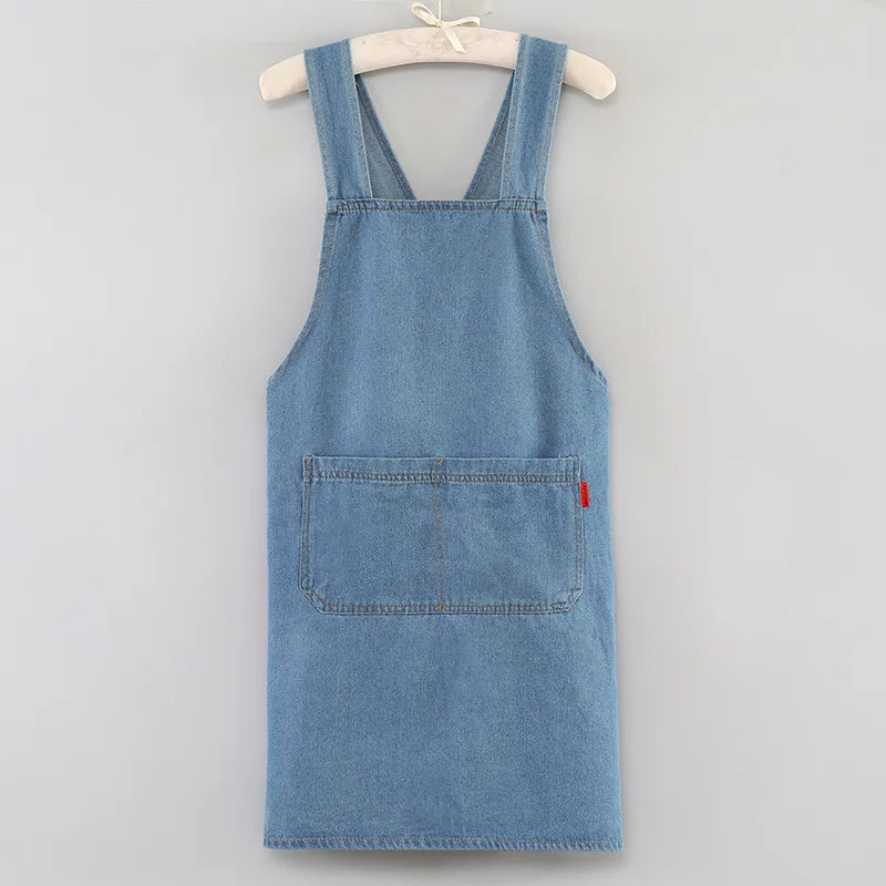 A light blue washed denim apron hanging on a wooden hanger.