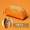 Orange leather key organizer wallet with zipper closure shown against an orange background.