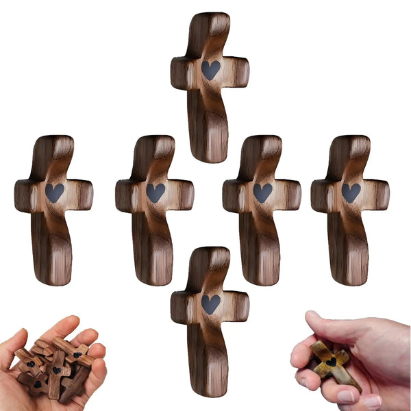 Eine Sammlung hölzerner Taschenkreuze in verschiedenen Größen und Finishes, gezeigt neben einer Hand, die ein kleines Kreuz h