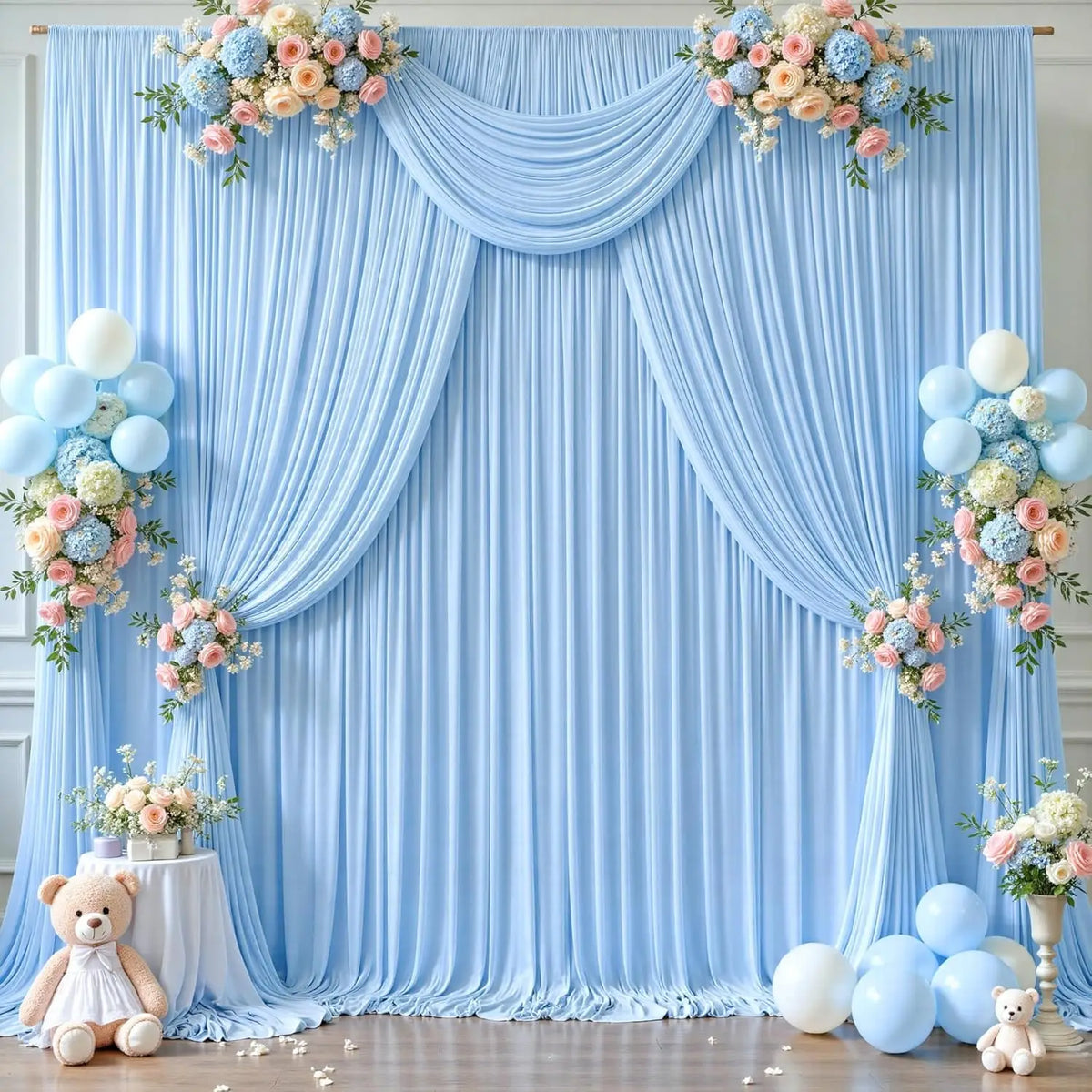 Fondo de tela azul claro con cortinas drapeadas, arreglos florales, globos y osos de peluche.