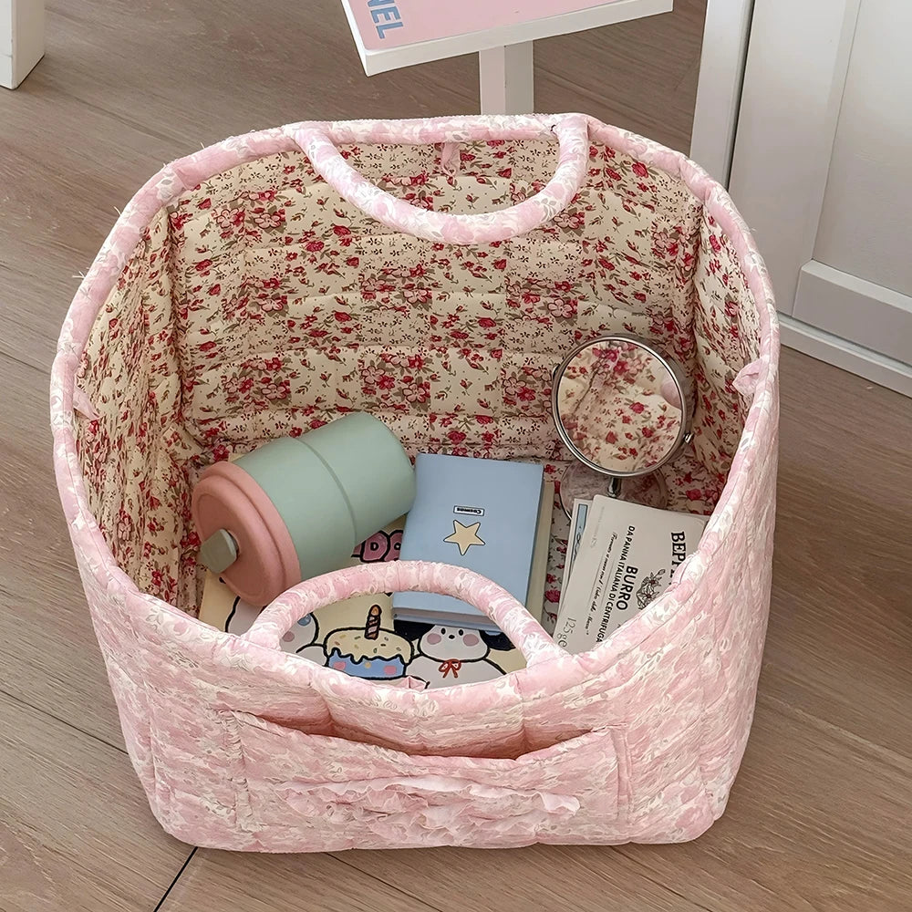 A pink vintage floral storage basket with a handle is shown, containing books and a small mirror.