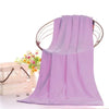 A purple ultra-absorbent microfiber bath towel hanging on a wooden hanger with floral accents.