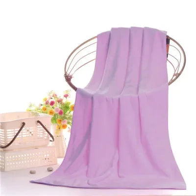 A purple ultra-absorbent microfiber bath towel hanging on a wooden hanger with floral accents.