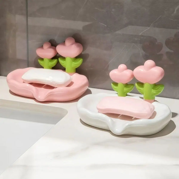 Pink and green decorative floral drain soap dishes with white soap bars on a marble surface.