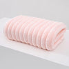 A rolled pink thickened microfiber bath towel lying on a white surface.