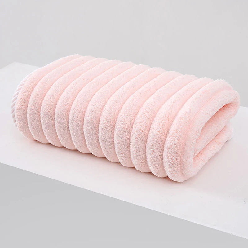 A rolled pink thickened microfiber bath towel lying on a white surface.