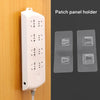 A white patch panel holder device is shown mounted on a wooden surface next to two clear adhesive wall hooks.