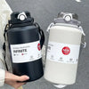 A hand holds a black stainless steel bottle with a lid and straw, next to a white insulated bottle.