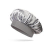 A silver satin sleep bonnet for toddlers, folded and displayed on a gray fabric base.