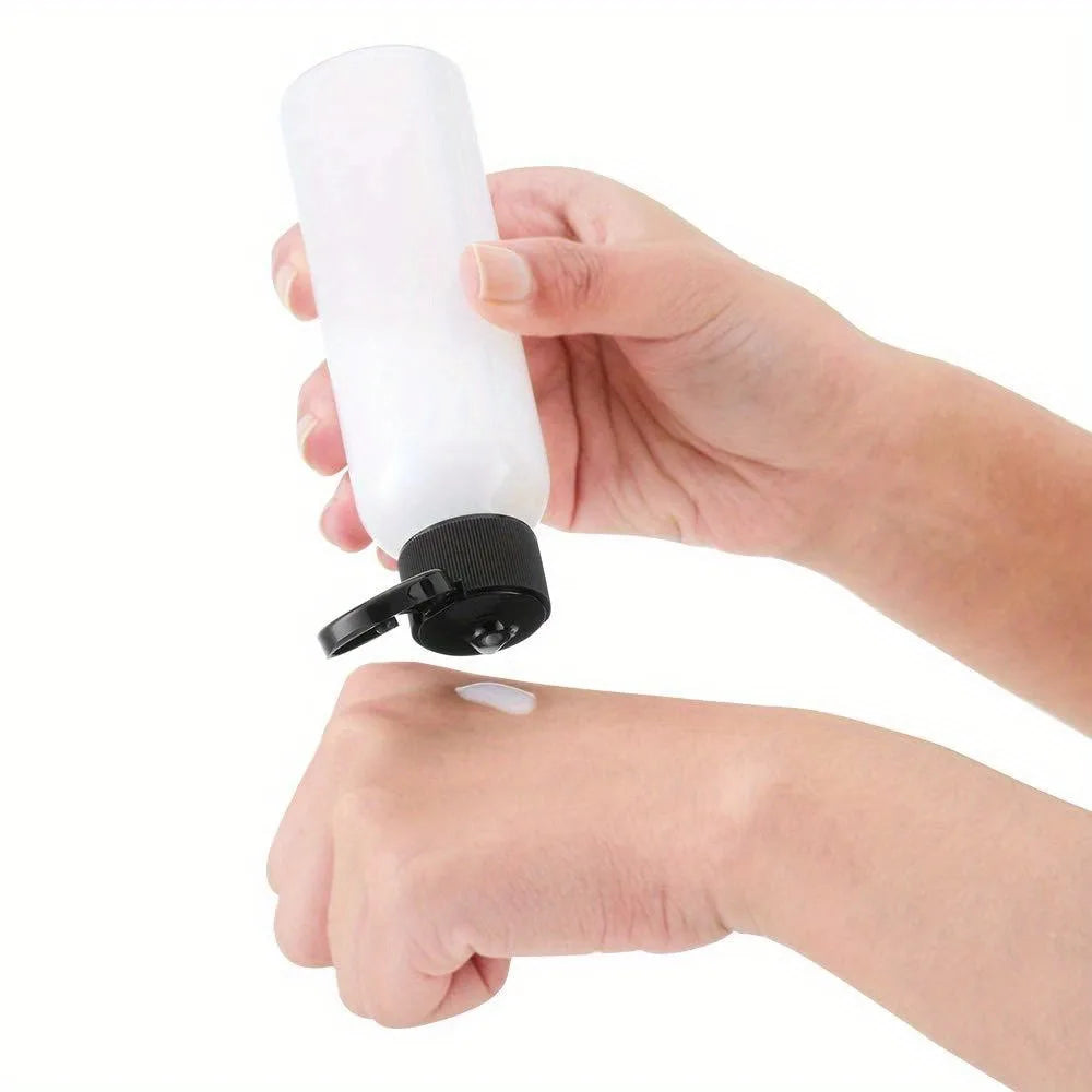 A hand is holding a white refillable travel bottle, demonstrating its use.