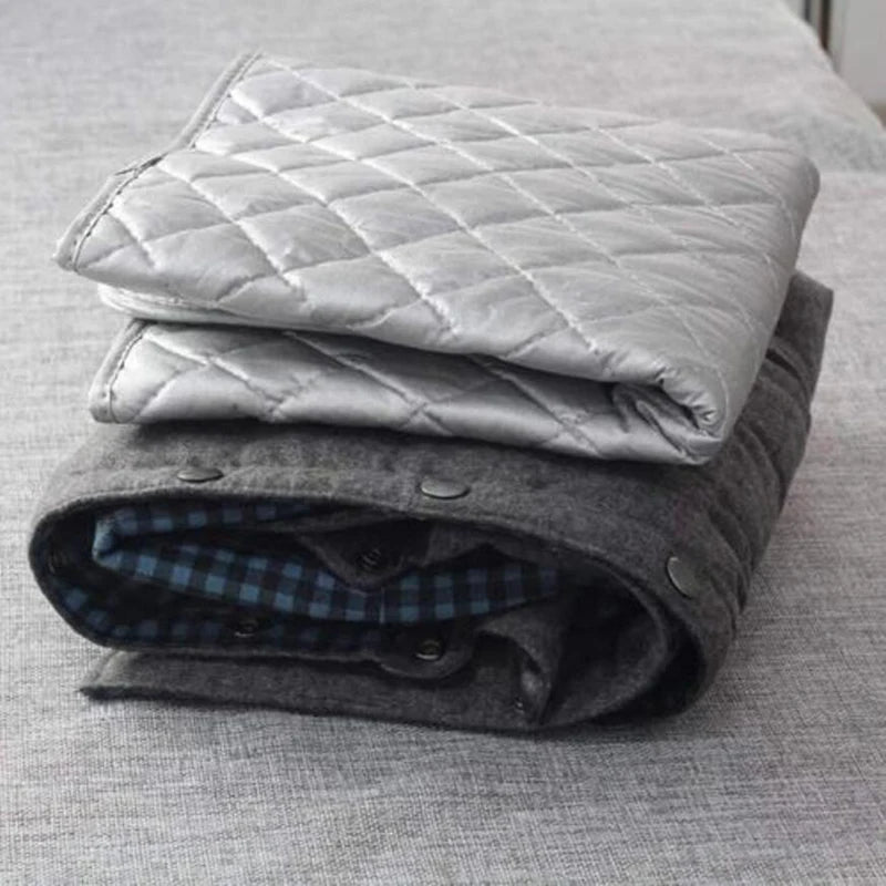 A stack of gray quilted ironing cloths and a folded dark blue plaid shirt on a light gray surface.
