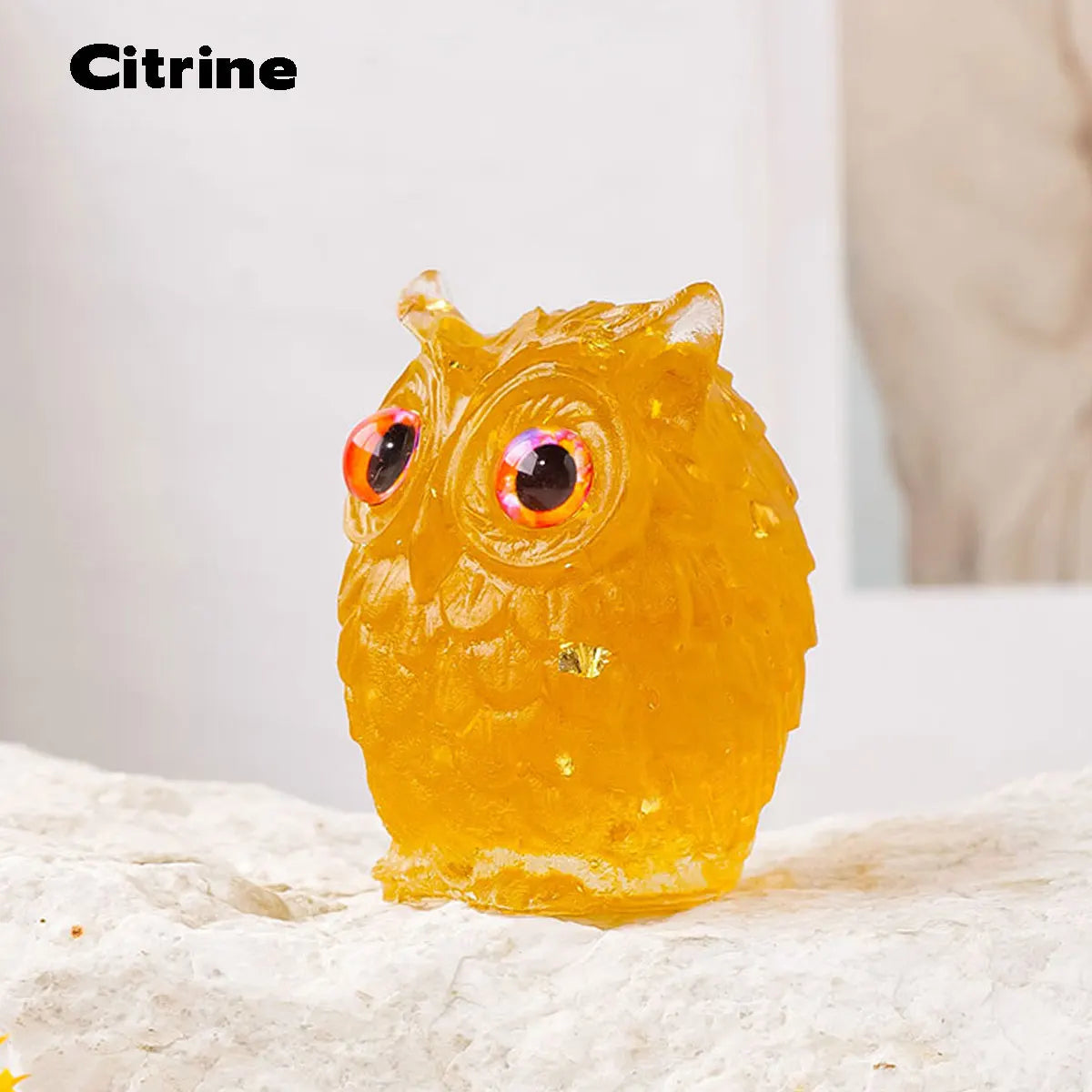 Tótem de búho de piedra natural triturada amarillo brillante con goteo, sobre una superficie blanca.