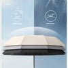 A large automatic folding umbrella in beige and black is shown against a light blue sky with rain falling.