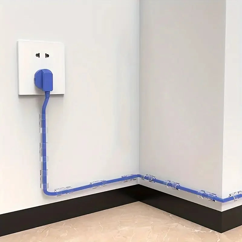 A blue adhesive cable clip is attached to a white electrical outlet and runs along the baseboard of a room.