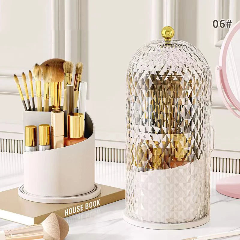 A clear spherical makeup brush organizer with a gold lid sits on a white tray next to various makeup brushes.