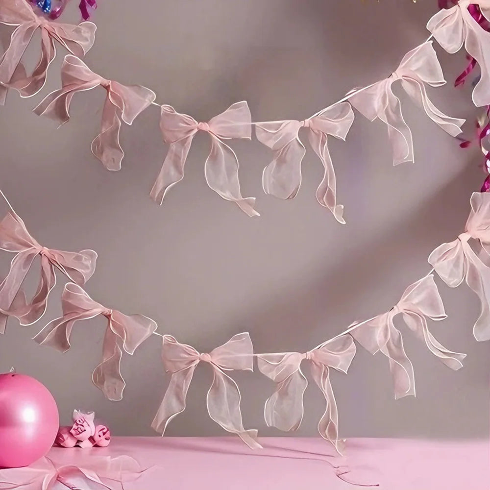 A delicate pink decorative bowknot banner garland set strung across a light gray background.