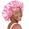 A woman wearing a pink satin sleeping cap tied in a bow