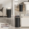 A black odor-sealing trash can with a press lid is shown on a modern bathroom counter and floor.