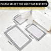 A set of gray and white microfiber bath mats are displayed next to a toilet and sink vanity.