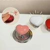 A collection of heart-shaped toilet presser buttons in pink, white, and red are displayed on a white surface.